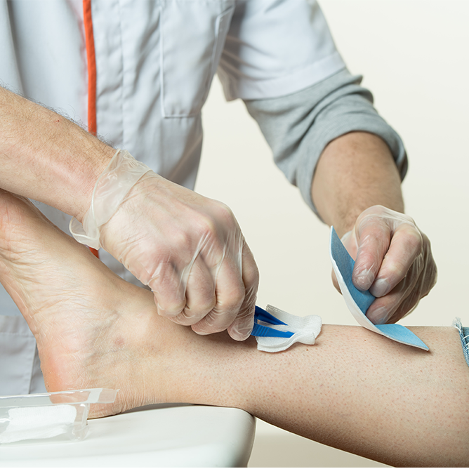 Infirmier pratiquant un pansement complexe sur la jambe d’un patient