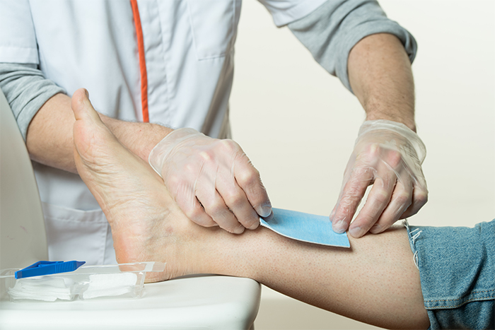Infirmier posant un pansement sur la jambe d’un patient
